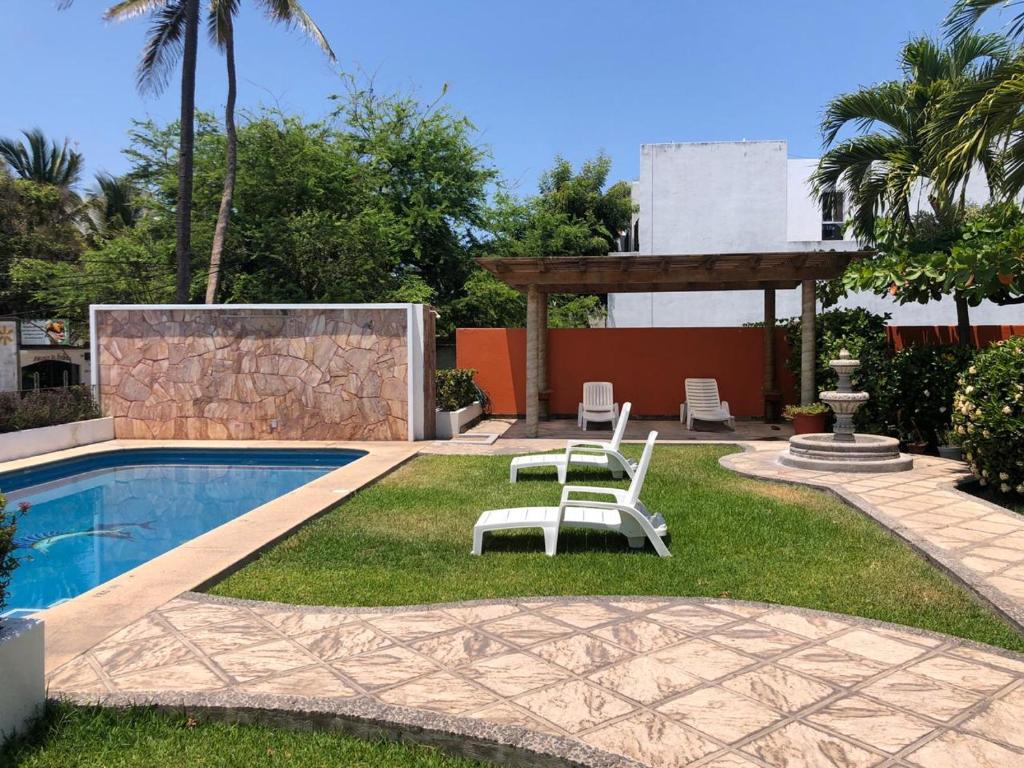 a pool with two chairs and a gazebo at Hotel Pez Vela in Manzanillo