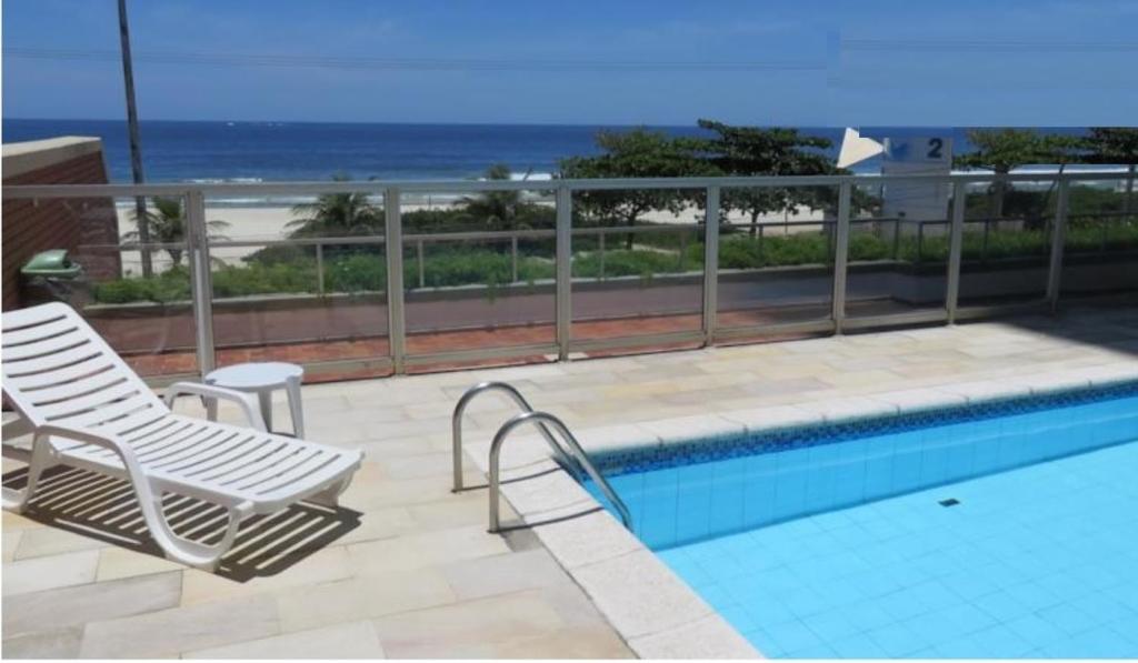 una piscina con 2 sillas de césped y el océano en Barra Beach, en Río de Janeiro