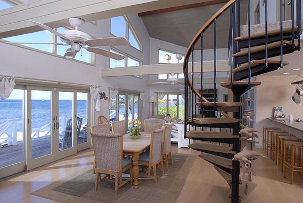una sala da pranzo con tavolo e scala a chiocciola di Castaway Cove by Grand Cayman Villas a North Side