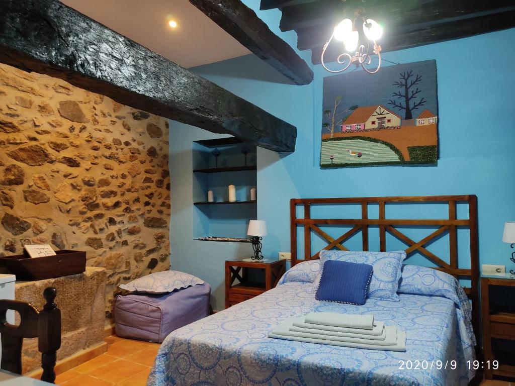 a bedroom with a bed and a stone wall at La Casa del Marqués in Logrosán