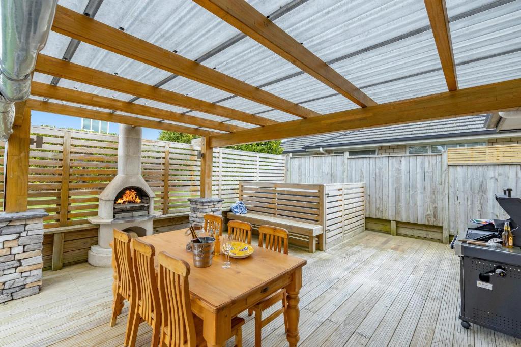un patio con mesa de madera y chimenea en Rise and Shine - Taupo, en Taupo