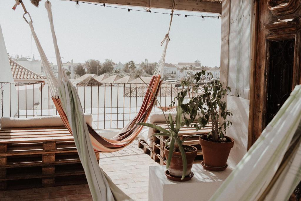 eine Hängematte auf einem Balkon mit Topfpflanzen in der Unterkunft Casa da Madalena Backpackers Hostel in Faro
