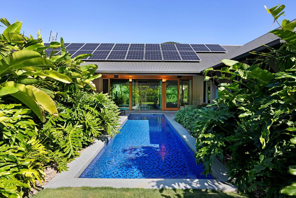 a house with a swimming pool with solar panels on the roof at Celeste - at Funnel Bay in Airlie Beach