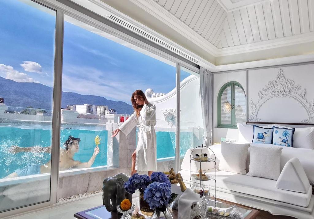 a woman standing in a room with a view of a pool at The Inside House in Chiang Mai