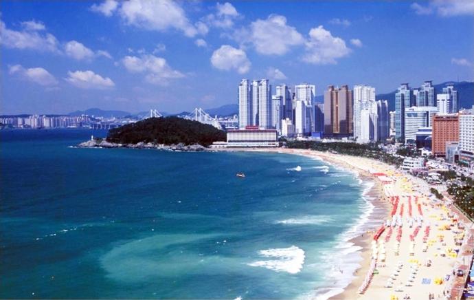 a beach with chairs and umbrellas and the ocean at Hotel Hyggelig in Busan