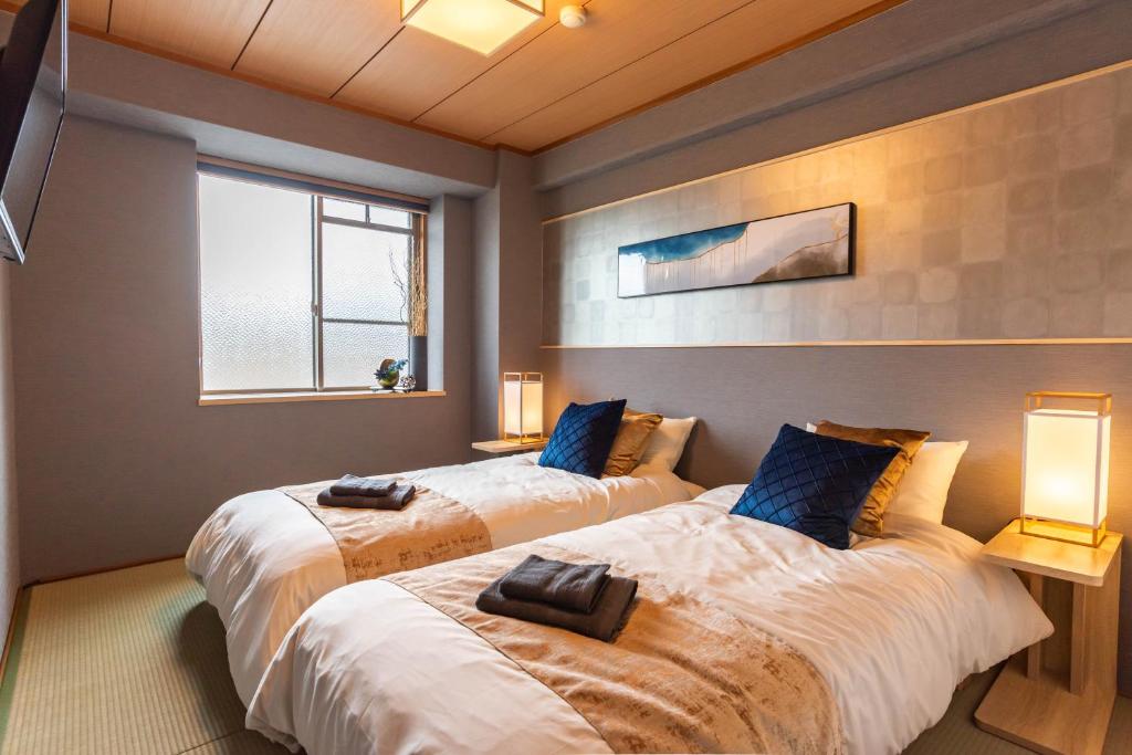 2 camas en una habitación con 2 lámparas y una ventana en design house ao, en Osaka