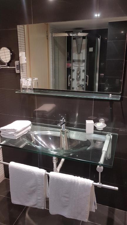 a bathroom with a sink and a mirror and towels at Cosmos Hotel in Rethymno