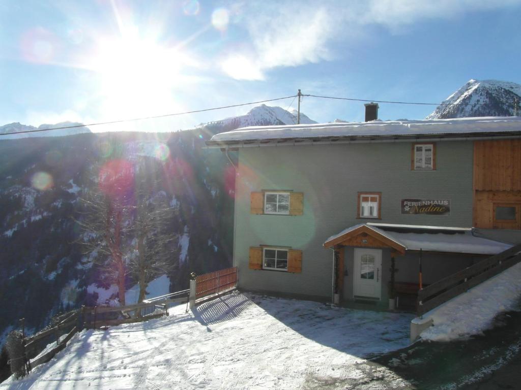 un edificio con nieve en el suelo junto a una montaña en Ferienhaus Nadine, en Kappl