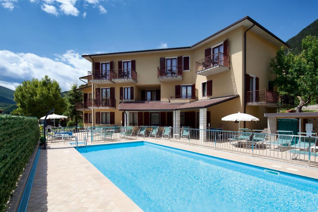 um hotel com piscina em frente a um edifício em Hotel Astra em Tignale