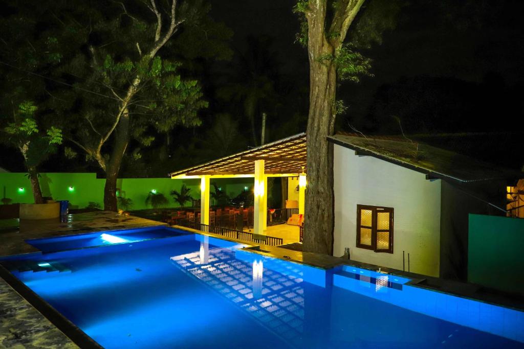 a swimming pool in front of a house at night at ilamparuma Hotel in Weligama