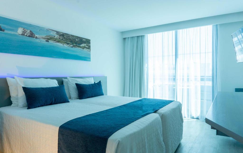 a bedroom with a large bed with blue walls at Anonymous Beach Hotel (Adults 16+) in Ayia Napa