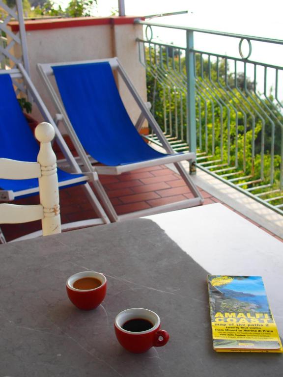 two cups of coffee on a table with a book and chairs at GIARDINO SUL MARE in Amalfi