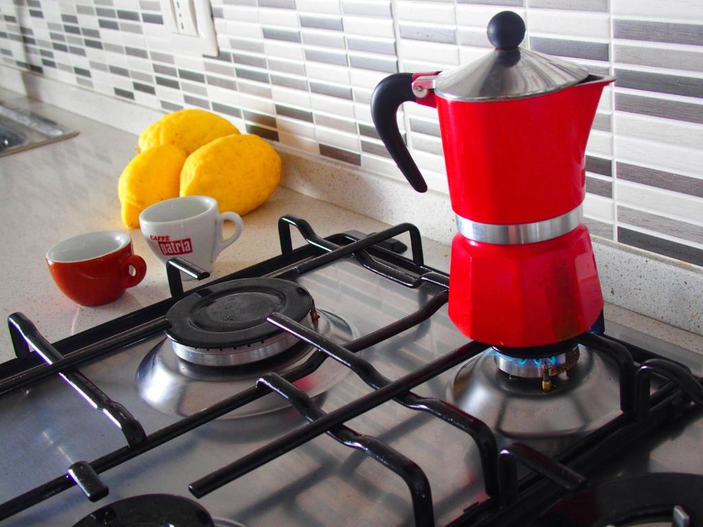 a red kettle on top of a stove with two oranges at GIARDINO SUL MARE in Amalfi