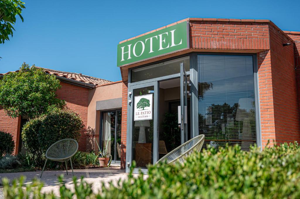 un hotel con due sedie di fronte a un edificio di Hôtel & Séminaire Le Patio Occitan - Toulouse Ouest - La Ramée a Cugnaux