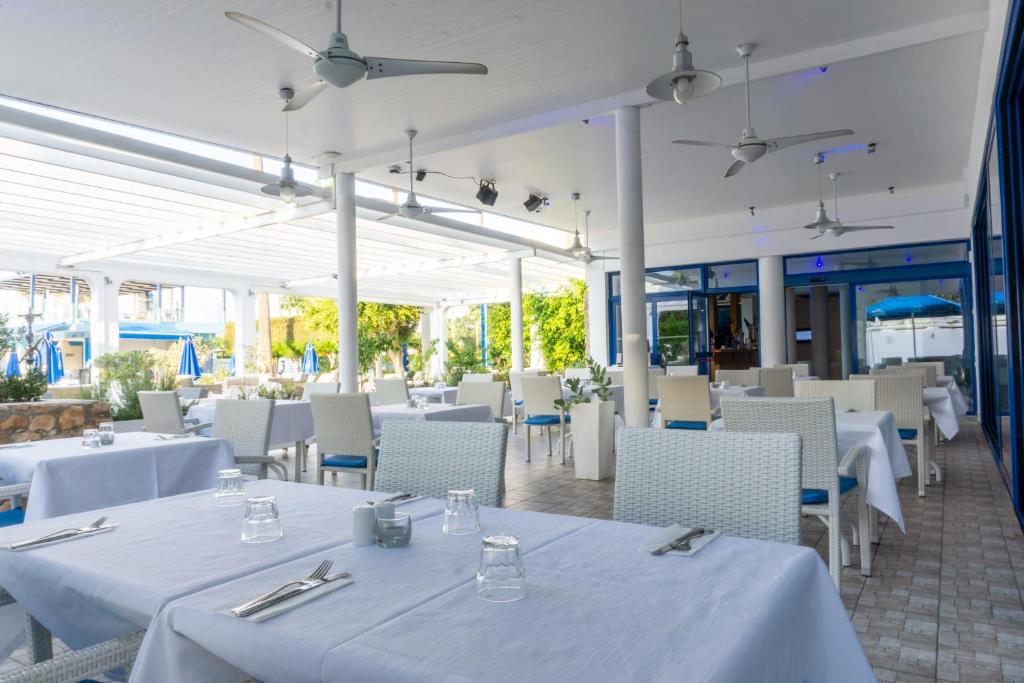 a restaurant with white tables and chairs and white tables and chairs at Anonymous Beach Hotel (Adults 16+) in Ayia Napa