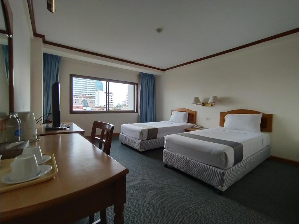 a hotel room with two beds and a desk at Sing Golden Place Hotel in Hat Yai