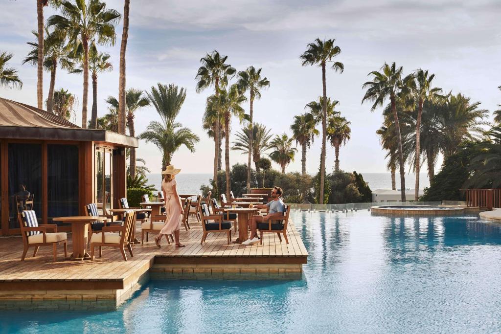 a couple sitting at a restaurant next to a swimming pool at Annabelle in Paphos