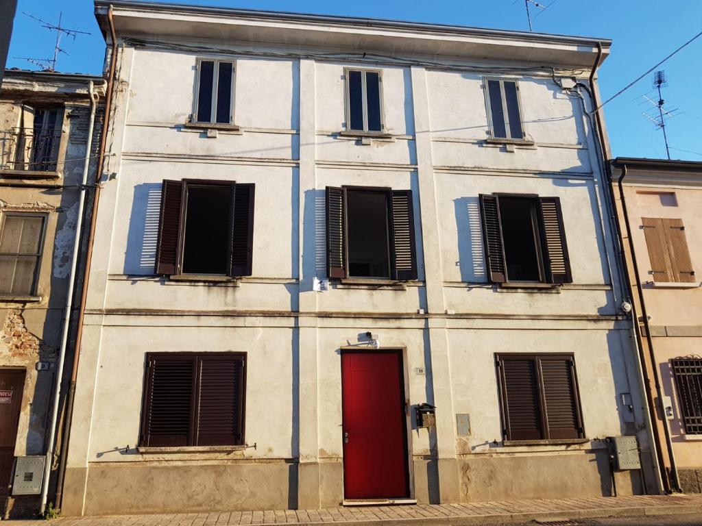 a white building with a red door and windows at Palazzo Adalgisa in Borgoforte