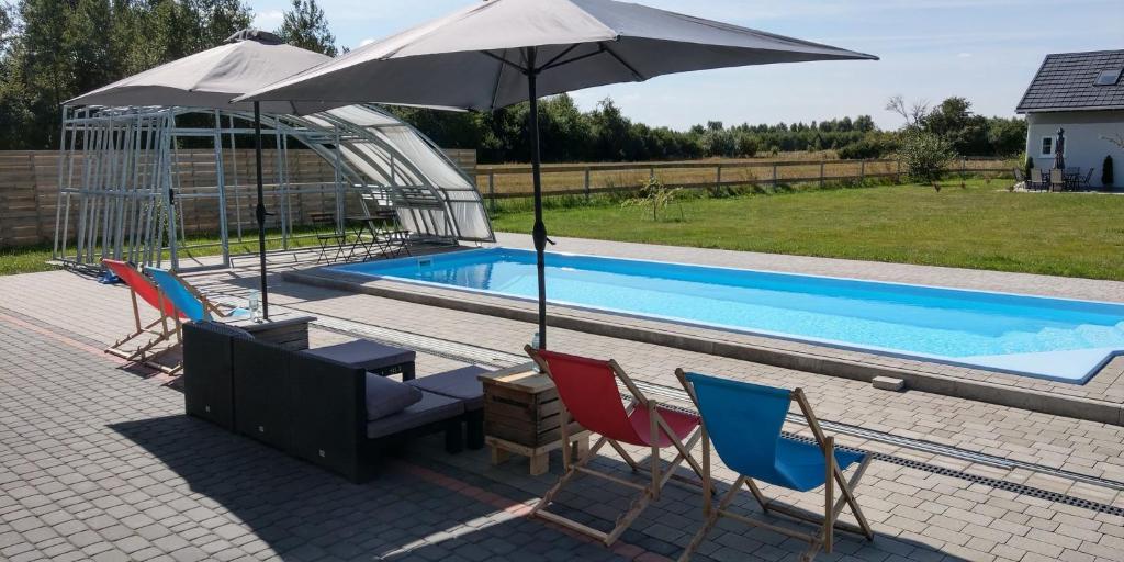 a patio with chairs and an umbrella next to a pool at Dom nad Pilicą in Wyśmierzyce
