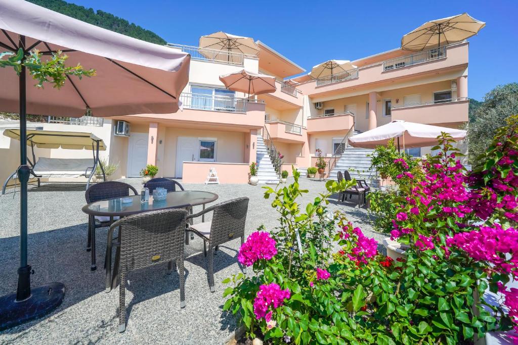 a patio with a table and chairs and flowers at Rani Apartments in Chrysi Ammoudia