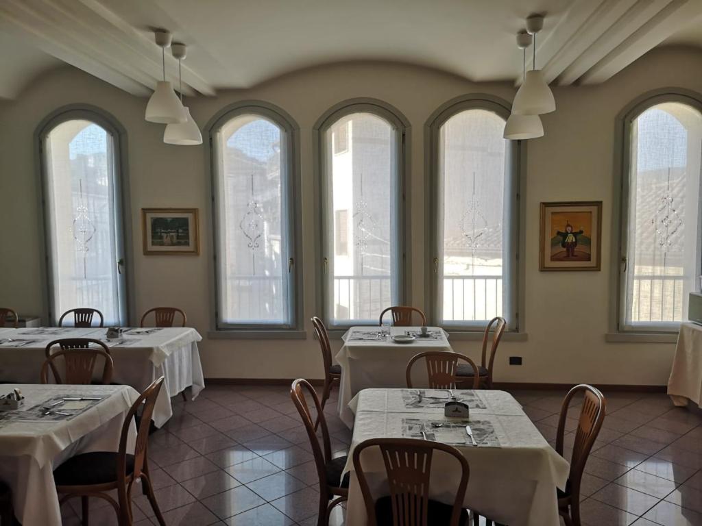 ein Restaurant mit weißen Tischen, Stühlen und Fenstern in der Unterkunft Hotel San Giuliano in Accettura