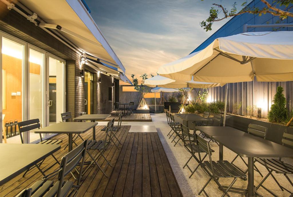 an outdoor patio with tables and chairs and umbrellas at BLO BY BLO HOTEL in Daegu