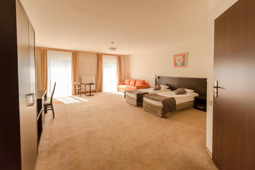 Large suite interior with two beds, orange sofa and twin windows letting in sunlight.