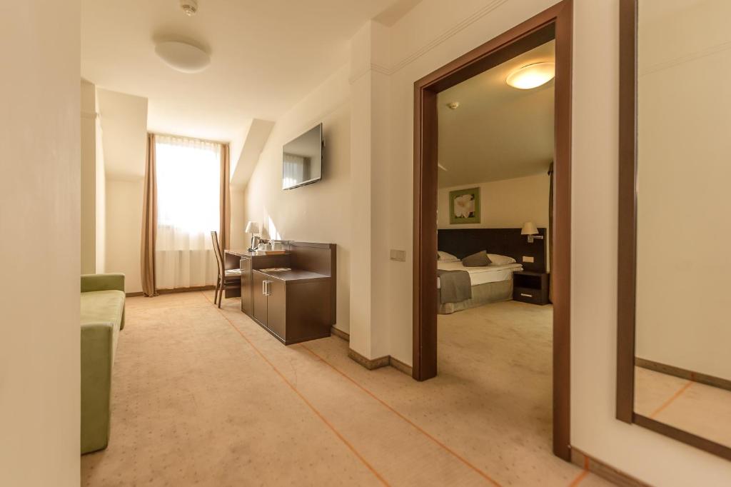 Hallway view into hotel suite with desk, wall-mounted TV and doorway revealing bedroom.
