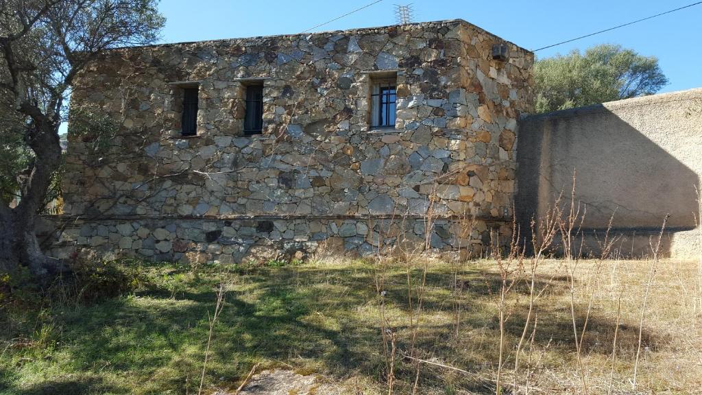 an old stone building with two windows on it at LE PAILLER 2P et 3 enfants sous le tipi in Calvi