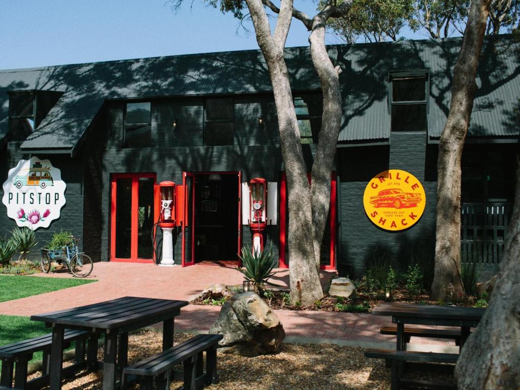 a black building with red doors and benches in front of it at PitStop Lodge in Gordonʼs Bay