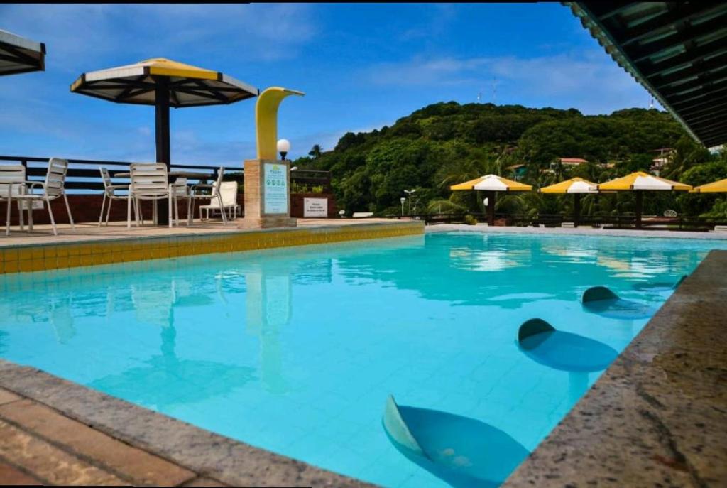 a swimming pool with blue water and umbrellas at Pipas Ocean Flat - Vista Mar in Pipa