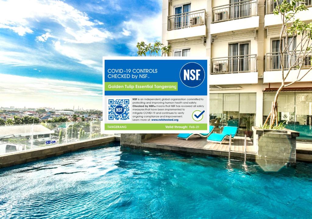 a sign in front of a building with a swimming pool at Golden Tulip Essential Tangerang in Tangerang