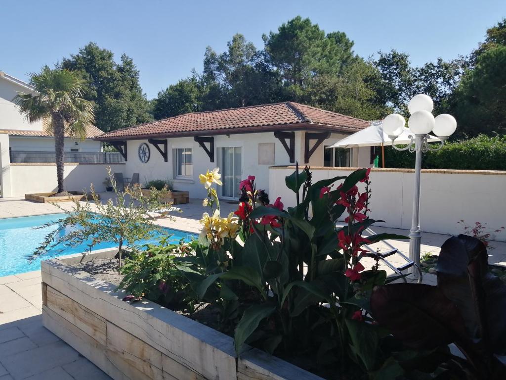 een huis met een zwembad en een tuin met bloemen bij Gîte l'Escapade au bassin d'Arcachon à Biganos in Biganos