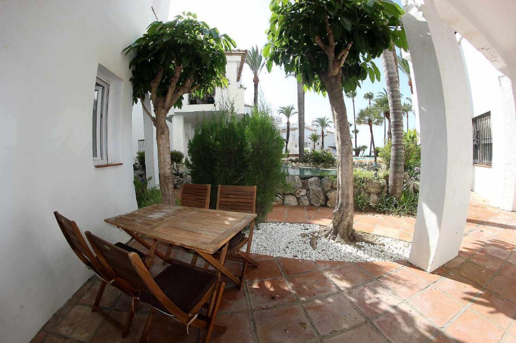een houten tafel en stoelen op een patio met palmbomen bij Fuente Duquesa in San Luis de Sabinillas