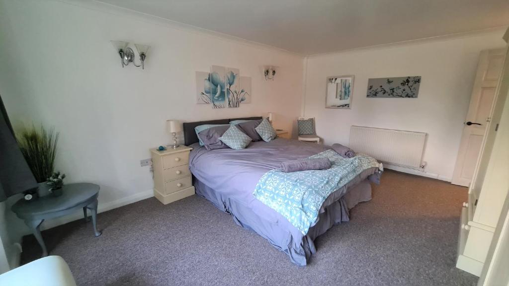 Schlafzimmer mit einem lila Bett und einem Schreibtisch in der Unterkunft Westbury House in Rochford