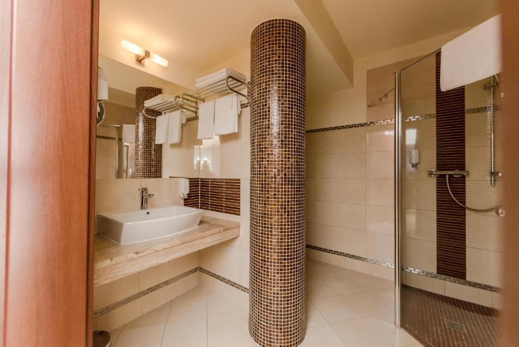 Modern bathroom featuring mosaic-tiled column, countertop sink and spacious walk-in shower