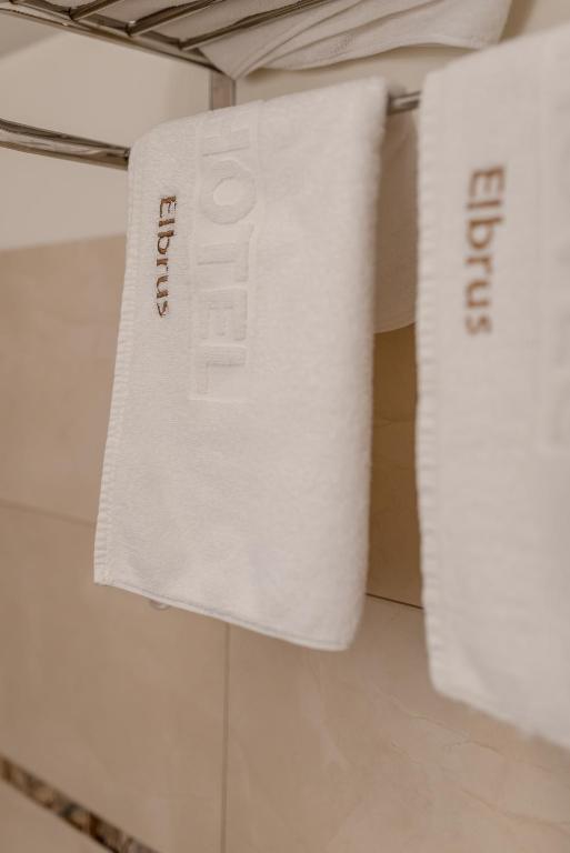 White hotel towels hanging on metal rack, embossed hotel name visible.