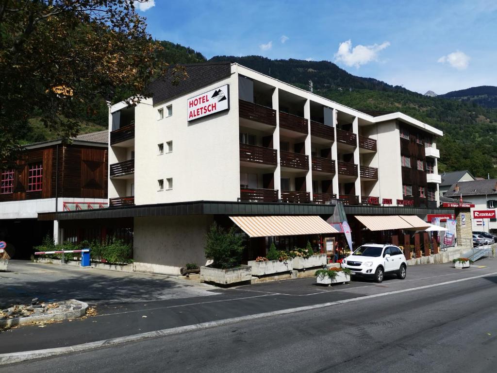 ein weißes Hotel mit einem davor geparkt in der Unterkunft Hotel Restaurant Aletsch in Mörel