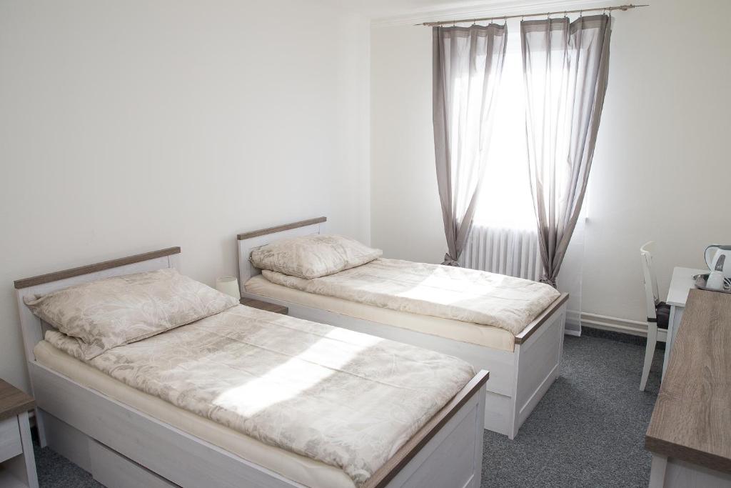 two beds in a room with a window at Penzion 68 in Kladno