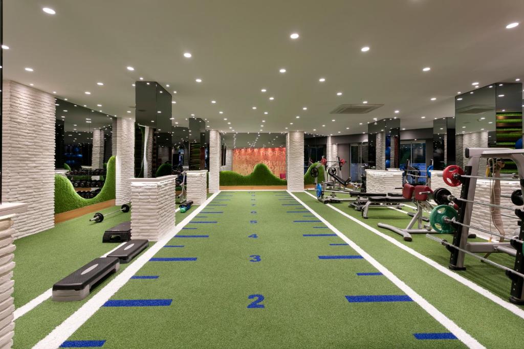 a gym with a green gym floor with machines at Limak Arcadia Sport Resort Belek in Belek