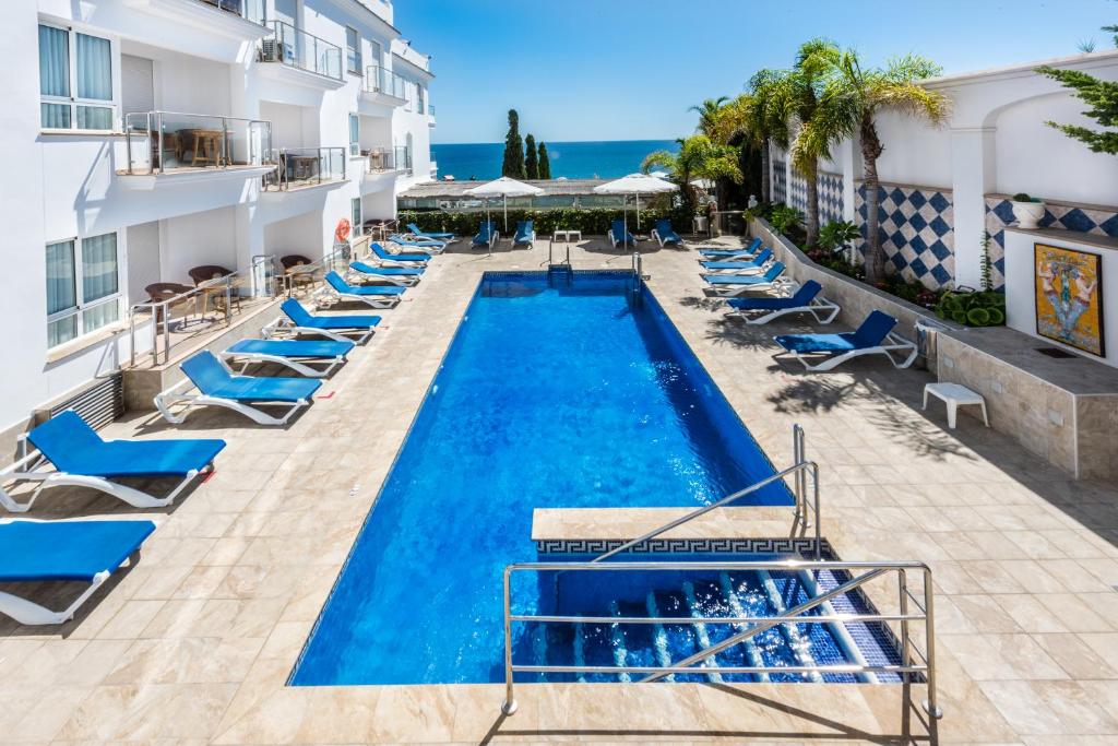 a beach with a pool, chairs, and tables at Toboso Apar - Turis in Nerja