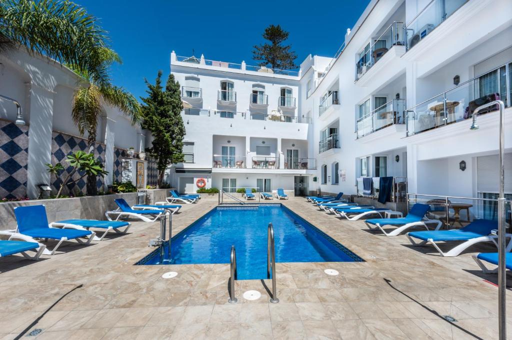 an image of a hotel swimming pool with blue chairs at Toboso Apar - Turis in Nerja