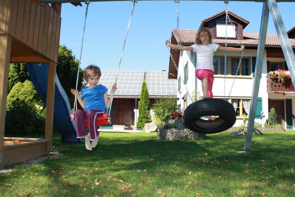 dos niños jugando en un columpio de neumáticos en un patio en Drexl-Hof en Schwifting