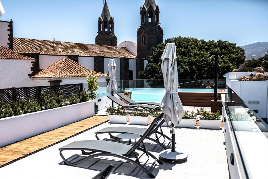 a patio with two umbrellas and a swimming pool at Hotel sXVI - Adults Only in Telde