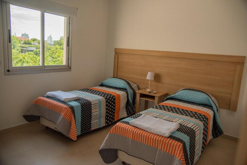 two beds in a room with a window at Morada Suites in Campana