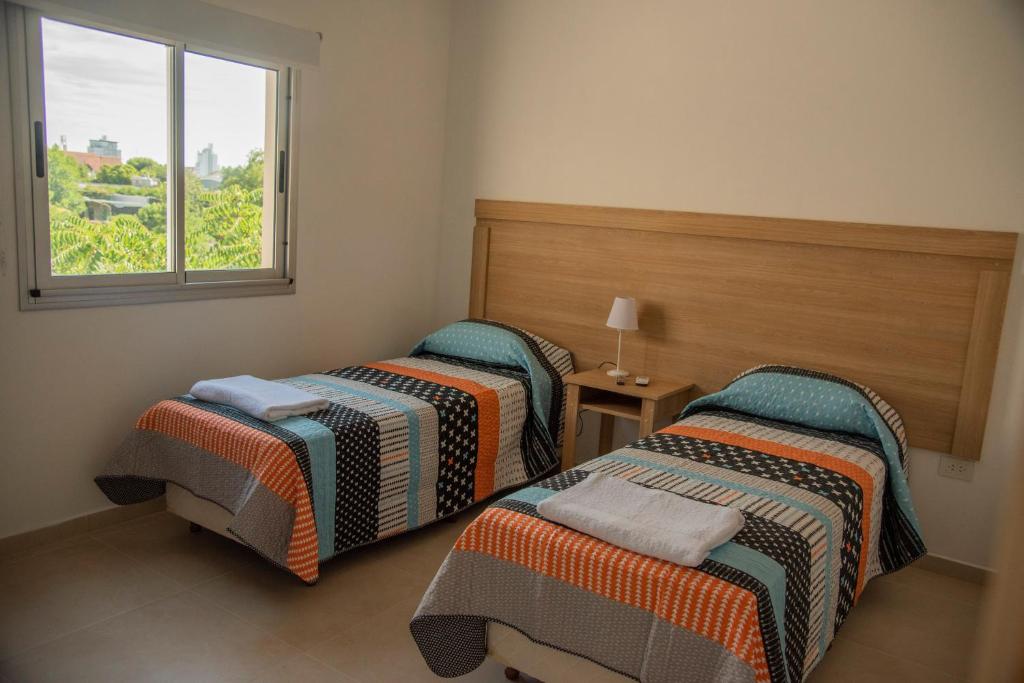 Duas camas num quarto com uma janela em Morada Suites em Campana