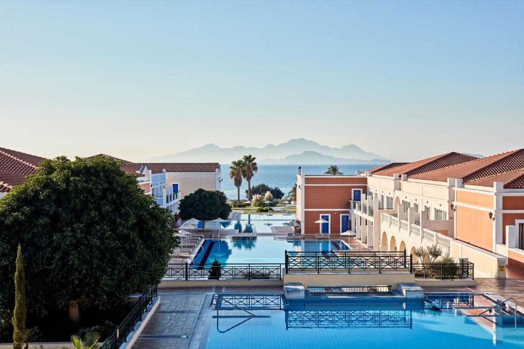 einen Blick auf den Pool in einem Resort mit Bergen im Hintergrund in der Unterkunft Porto Bello Royal in Kardamaina
