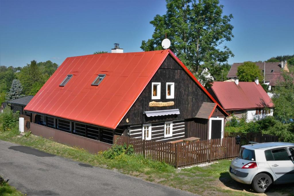 ein Haus mit einem orangenen Dach mit einem Auto davor geparkt in der Unterkunft Chaloupka u lišáka in Sněžné