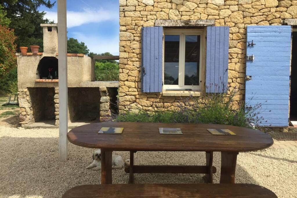 a wooden table in front of a building with a bear at Cabanon de charme en plein coeur des vignes in Pertuis