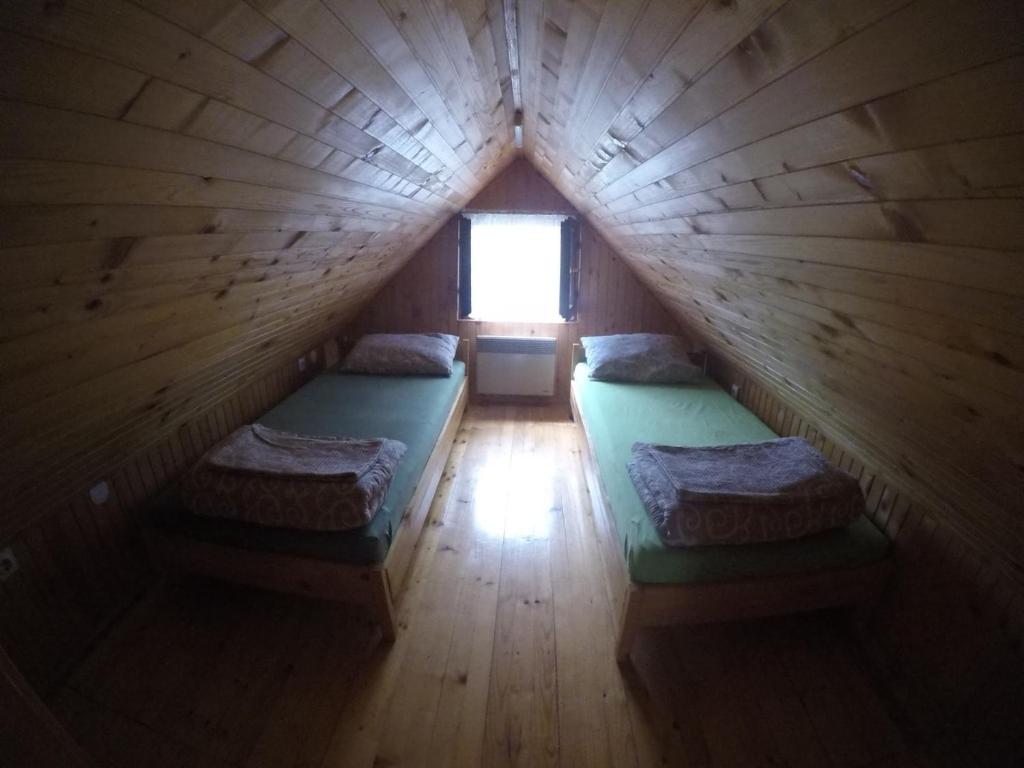 a room with two beds in a wooden attic at Medeni sat Mecavnik in Mokra Gora